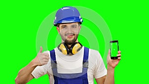Builder holds a phone in his hands and shows a thumbs up. Green screen. Mock up