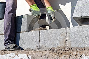 A builder holds a trowel during the construction of a wall made of aerated concrete blocks