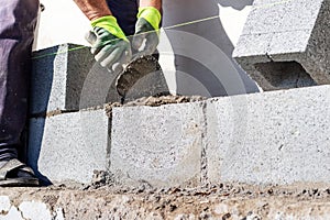 A builder holds a trowel during the construction of a wall made of aerated concrete blocks