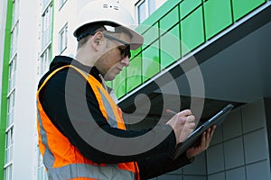 Builder inspects the new building, writing down comments in the tablet.. Building inspector.