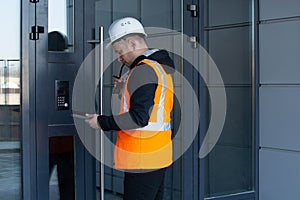 Builder inspects the new building, writing down comments in the tablet.. Building inspector.