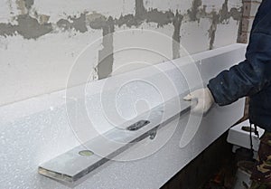 Builder install styrofoam insulation board and measuring with spirit level. Exterior Foam Insulation