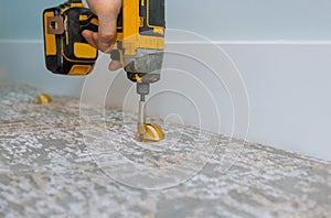 Builder in installing doorstop in a modern house, in using screwdriver photo