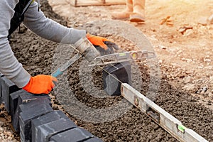 Builder installing paving blocks during road and footpath construction on semi-dray concrete mix