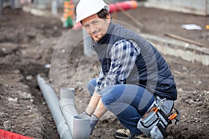builder installing waste pipes outdoors