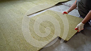 The builder insulates the floors of the house with glass wool. Laying glass wool on a concrete floor.