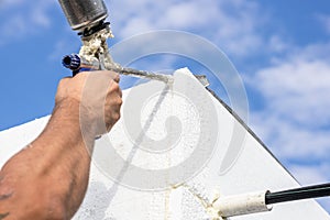 The builder insulates the walls of the house with polystyrene foam and fills the gaps with polyurethane foam. A gun with foam in