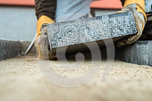 Builder laying a paving brick placing it on the sand foundation