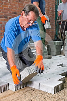 Builder laying paving stones around a new house.