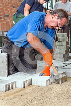 Builder laying paving stones with his team.