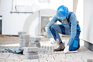Builder laying paving tiles