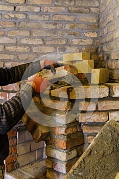 The builder lays down the bricks for the fireplace and fastens them with cement mortar