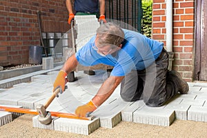 Builder levelling paving stones as he lays them. photo