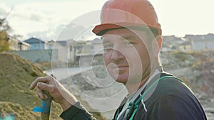 Builder looking at camera and smiling at construction site.