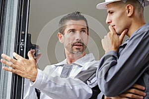 builder looking at window mechanism with apprentice