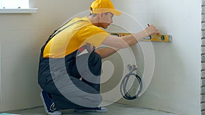 Builder makes markings on the wall using a level tool.