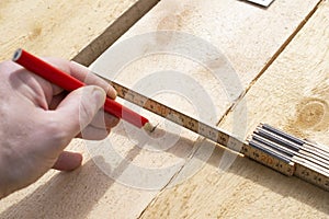 Builder makes marks on a wooden board for future use