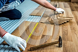 The builder, man is engaged in laying laminate wood floor in the room - repair and finishing work.