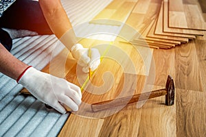 The builder, man is engaged in laying laminate wood floor in the room - repair and finishing work.