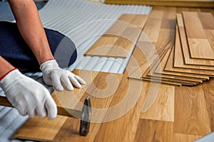 The builder, man is engaged in laying laminate wood floor in the room - repair and finishing work.