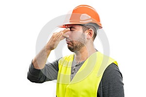 Builder man making grossed expression holding nose as bad smell photo
