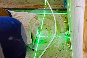 The builder measures the repair lines using a green laser level