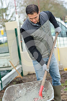 Builder mixing cement in wheelbarrow