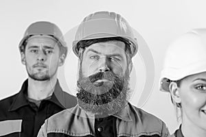 Builder near colleagues. Bearded labourer concept. Man with beard