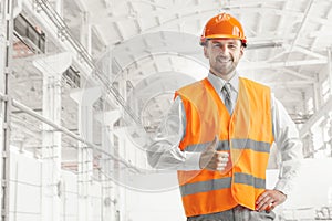 The builder in orange helmet against industrial background