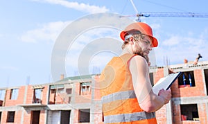 Builder orange vest and helmet works at construction site. Control construction process. Contractor control according to