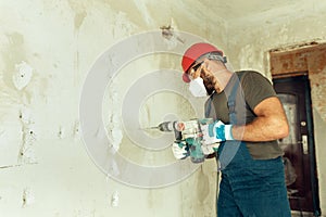 Builder with perforator drills holes in concrete wall