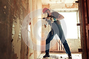 Builder with perforator drills holes in concrete wall