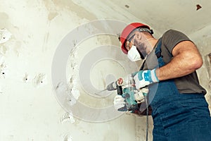 Builder with perforator drills holes in concrete wall
