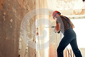 Builder with perforator drills holes in concrete wall