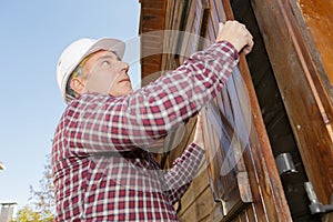 builder placing wooden blinds outoors