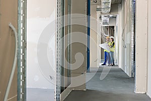 Builder with plan inspecting the construction site