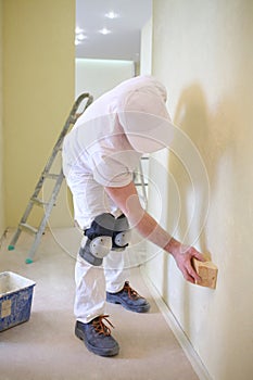 Builder polishing the wall using a sanding photo