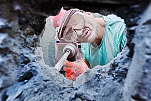 Builder pounding chiseling into tough concrete with rotary hammer.
