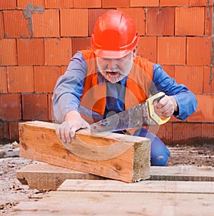 Builder in protective helmet cutting wood board with saw. Professional Construction Worker Carpenter in hard hat.