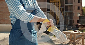 Builder putting on protective gloves at construction site