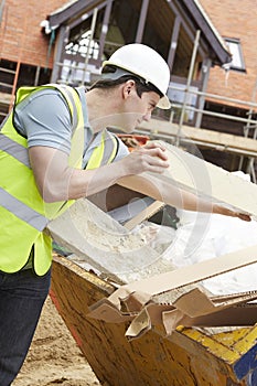 Builder Putting Waste Into Rubbish Skip