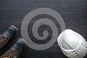 Builder's helmet and boots on a wooden background, top view.