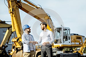 Builder with a sales consultant at the shop with heavy machinery