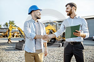 Builder with a sales consultant at the shop with heavy machinery