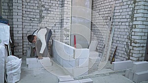 Builder sawing aerated concrete block with hand saw