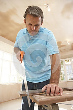 Builder Sawing Wood On Workbench