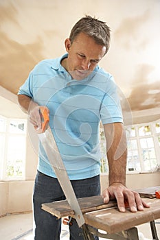 Builder Sawing Wood On Workbench