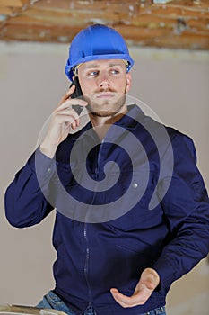 builder shrugging while talking on smartphone