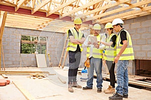 Builder On Site Looking At Digital Tablet With Apprentices