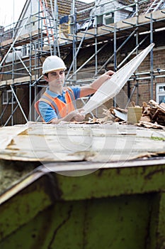 Builder On Site Putting Waste Into Rubbish Skip